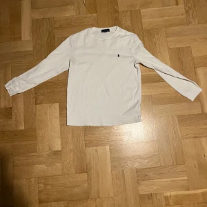 Vit långärmad tröja från Polo Ralph Lauren - Säljer en stilren vit långärmad tröja från Polo Ralph Lauren. Tröjan har en liten broderad logotyp på bröstet och är tillverkad i ett mjukt material. Perfekt för en avslappnad och klassisk look. Priset kan diskuteras. På tröjan står det att det är 14-16 år men det passar Xs kanske S