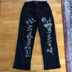 Svarta byxor med mönster - Svarta mjukis byxor från Racerworldwide. Köpta i japan perfekt skick. Metall mönster på framsidan. Loose fitting.