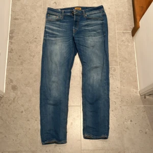 Blåa Stonewash JacknJones jeans - Säljer ett par Jack and Jones blåa stonewash jeans med en straight passform. De är i bra skick förutom det lilla hålet längs ner i byxan. Storlek 33/32, Modellen i bilden är 183 cm lång Och väger 78Kg. Ny pris: 899kr mitt pris: 349kr