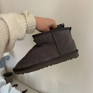 Grå boots från UGG - Säljer ett par grå boots från UGG i mocka. De har en klassisk design med en låg profil och en bekväm sula. Perfekta för kyligare dagar. Oanvända 