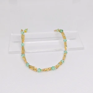 Grönt armband med gulddetaljer - Säljer ett grönt armband med guldfärgade stavar. Perfekt för att lägga till en färgklick till din outfit. Armbanden har en fin kedja och är lätta att matcha med andra smycken. OBS! Denna annons gäller endast det gröna armbandet.