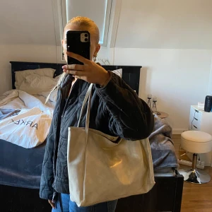 Beige axelväska i syntet - Snygg och rymlig beige axelväska i syntetmaterial. Perfekt för att bära med sig alla nödvändigheter. Enkel design med långa handtag för bekväm användning. Litet bläck sträck på näst sista bilden som syns på bilden