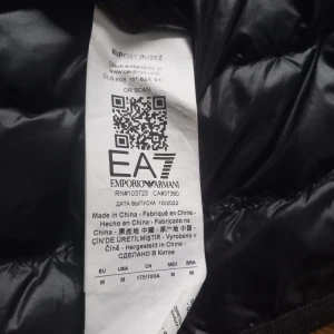 Svart väst från Emporio Armani - Snygg svart väst från Emporio Armani med EA7-logga. Jackan har en quiltad design och dragkedja framtill. Perfekt till sommaren....