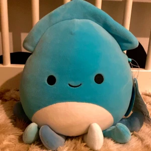 Blå Squishmallow Sky - Säljer en supermjuk och gosig blå Squishmallow vid namn Sky. Den har en söt design med ett leende ansikte och vita detaljer. Perfekt för kramar och som dekoration i rummet. En härlig presentidé för alla åldrar! Inga defekter va ja vet❤️