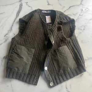 Olivgrön stickad väst från Zara - Säljer en mörkgrön stickad väst från Zara med stora fickor och knappar framtill🥰Aldrig använd och med lappen kvar!