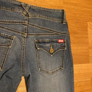 Lågmidjade y2k jeans - Jättecoola lågmidjade jeans‼️De har vackra detaljer vid fram och bakfickorna samt dragkedjor längst ner 🙏Köpta second hand därför lite slitna på vissa ställen (se sista bilden tex) priset är diskuterbart 💗 kontakta mig gärna vid frågor eller mått! 🍁