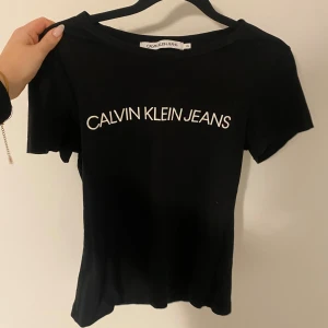 Calvin Klein t-shirt  - JÄTTE BRA SKICK!! Snygg svart t-shirt från Calvin Klein Jeans med vit logotyp på bröstet. Perfekt för en stilren och avslappnad look.