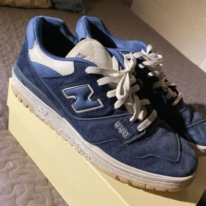 Blå New Balance 550 sneakers - Snygga blå New Balance 550 sneakers med vita detaljer och snörning. Skorna har en robust sula och är perfekta för en avslappnad stil. Den klassiska New Balance-loggan syns på sidan och hälen. Säljer skorna då jag inte använder dom längre. Hör gärna av dig vid några frågor. 