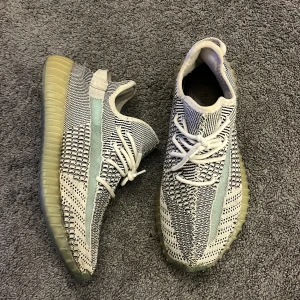 Adidas Yeezy Boost 350 V2 - Snygga Adidas Yeezy Boost 350 V2 sneakers i en stilren kombination av svart och vit med en genomskinlig sula. Skorna har ett unikt mönster och snörning för en perfekt passform.