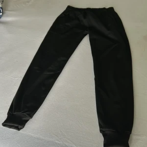 Svarta mjukisbyxor från Burberry - Snygga svarta mjukisbyxor från Burberry med broderad logga. Perfekta för en avslappnad stil. Elastisk midja och muddar vid bensluten för extra komfort.