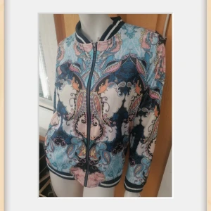 Mönstrad zip tröja från ONLY - Jätte fin Zip tröja från ONLY med ett unikt mönster i blått, rosa och svart.  har dragkedja framtill och ribbade muddar vid ärmslut och nederkant. 2 fickor. Stort nummer 52 på ryggen ger en sportig touch.