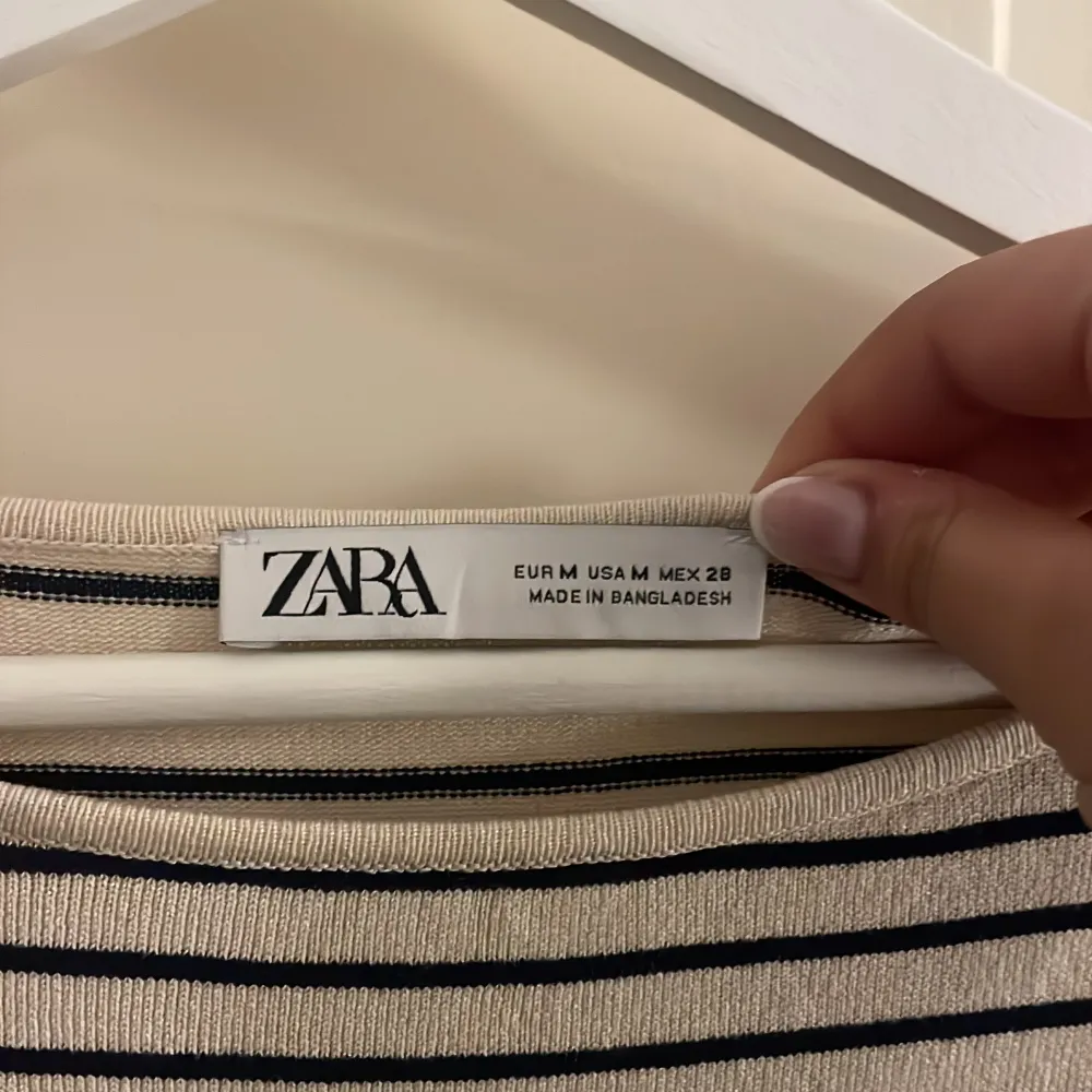 Säljer en stilren randig tröja från Zara i beige och svart. Tröjan har en avslappnad passform med långa ärmar och rund halsringning. Perfekt för en casual look.. Neuletakit & Villapaidat.
