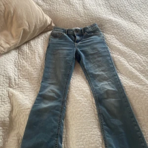 Blå flared low waist  jeans från Lindex - Säljer ett par klassiska blå jeans från Lindex. De har en straight passform och är perfekta för en avslappnad stil. Jeansen har snygga detaljer på bakfickorna och är tillverkade i ett slitstarkt denimtyg. Inga skador eller slit på. 
