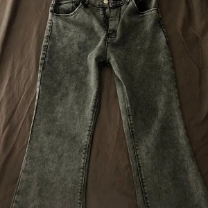 Grå jeans med bootcut - Snygga grå jeans med bootcut-stil och klassisk femficksdesign. De har en knapp och dragkedja framtill. Perfekta för en avslappnad look.