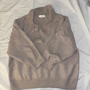 Beige tröja med krage - Säljer en stilren beige tröja med krage och v-ringning. Tröjan har trekvartsärmar och en avslappnad passform, perfekt för en bekväm och snygg look.