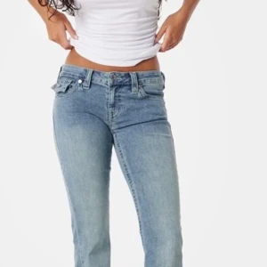 lågmidjade Blå jeans från True Religion - Snygga blå jeans från True Religion med låg midja och bootcut-stil. De har klassiska femficksdetaljer och märkets ikoniska logga på bakfickan. Perfekta för en avslappnad look. Helt nya med prislapp och är endast testade. Säljer då dem är för stora och bytesrätten har gått ut. 