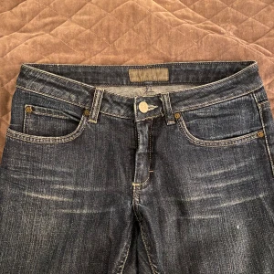 Mörkblå low waist jeans från Acne - Snygga mörkblå low waist jeans från Acne med klassisk femficksdesign och knappgylf. Perfekta för en stilren look. Märkeslappen sitter på baksidan av midjan. Toppen skick förutom att de har lite färg på benen, vilket jag tror går bort i tvätten, har inte testat 💕                                                                       Midja - 40 cm                                                         Inneben - 94 cm