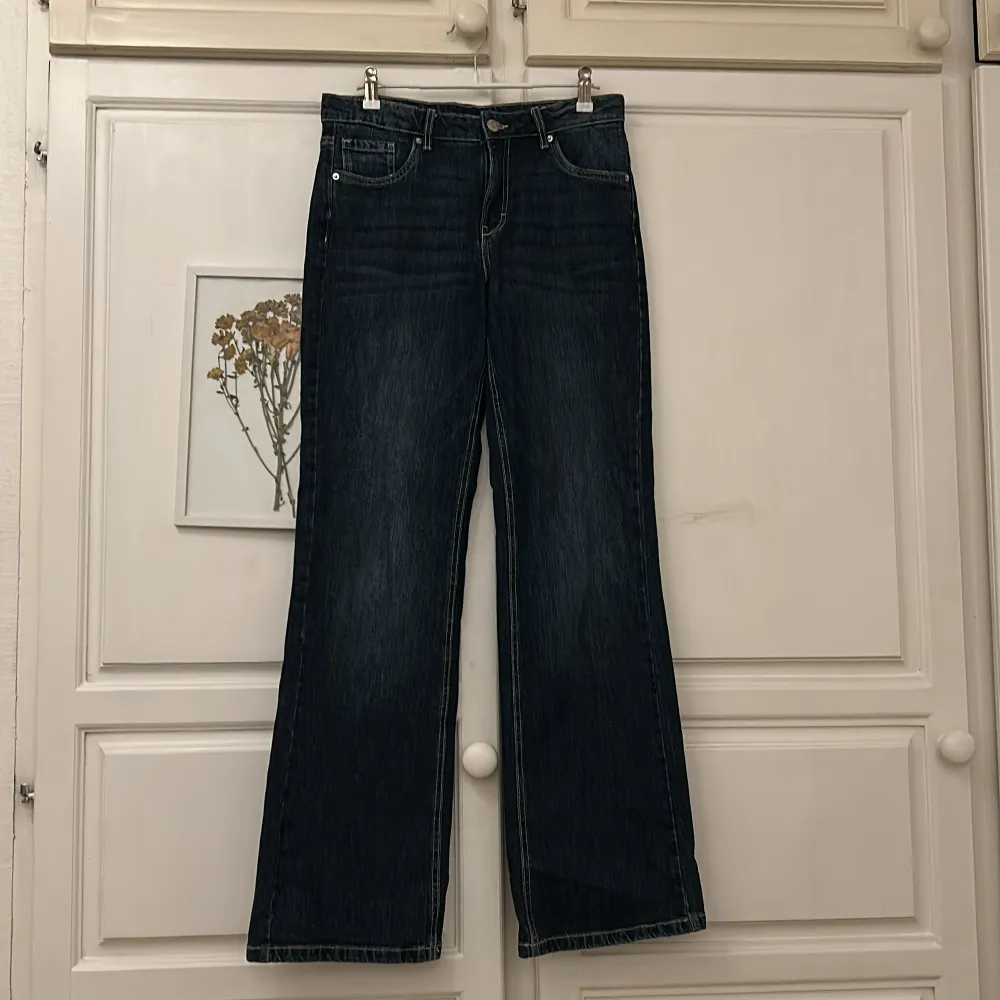 Snygga mörkblå jeans från Kappahl med raka ben och klassisk femficksdesign. Jeansen har knappar på bakfickorna och en bekväm passform. Perfekta för en avslappnad stil.ny pris 379kr. Farkut & Housut.