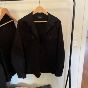 Svart owershirt från gabba - Snygg svart jacka från Gabba med knappar framtill och klassisk krage. Perfekt för en stilren look. Den är i M och är alldrig använd! Nypris 999kr mitt pris 350kr. Skriv vid någon fundeing eller vid föer bilder osv!
