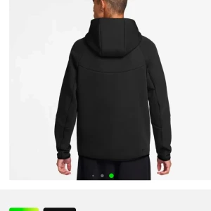 Nike tech tröja  - Snygg svart jacka från Nike med dragkedja och huva. Perfekt för kyligare dagar med sin stilrena design och praktiska ficka på ärmen.