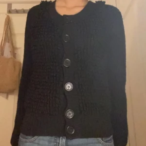 Svart kofta från Sonia Rykiel för H&M - Snygg svart kofta från Sonia Rykiel för H&M med stora knappar framtill. Koftan har en texturerad stickning och långa ärmar, perfekt för kyligare dagar.