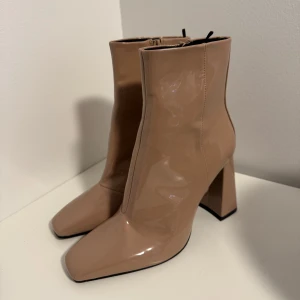 Beige boots  - Helt nya boots med klack och dragkedja. De har en glansig finish och en fyrkantig tå. Små märken har uppstått men inget att anmärka på