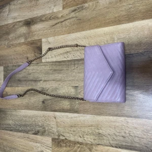 Rosa quiltad axelväska - Snygg rosa axelväska med quiltat mönster och kedjerem. Perfekt för att ge en färgklick till din outfit. Väskan har en stilren design och är lätt att matcha med olika stilar.