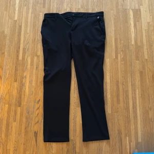 Svarta kostymbyxor - Snygga svarta kostymbyxor från Blend med en klassisk straight passform. Byxorna har knappar och dragkedja framtill samt fickor både fram och bak. Perfekta för en stilren look.