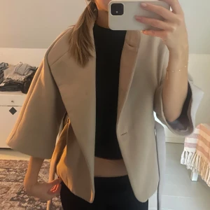 Beige kappa med knytband - Snygg beige kappa med trekvartsärm och knytband i midjan. Storlek XL men passar mig med S. (Knapparna är borta 
