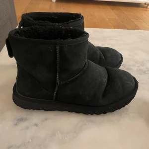 Svarta boots från UGG - Säljer ett par svarta UGG boots i mocka. De är varma och perfekta för kyligare väder. Skorna har en robust sula och en mjuk insida för extra komfort. Strl 42 , använt skick 