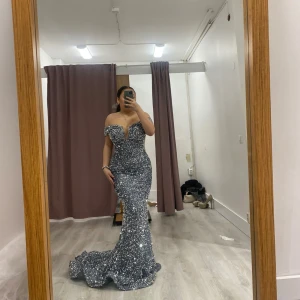 Festklänning/ Balklänning  - Säljer en fantastisk glittrig klänning med offshoulder-design och en elegant lång siluett. Klänningen perfekt för speciella tillfällen. Den är figurnära och framhäver formerna på ett smickrande sätt. Den är uppsydd och passar mig perfekt när jag har klackar och jag är 155cm lång. Har endast användt en gång under ett par timmar så skicket är som ny. Köpt på pink and purple i malmö för 3700kr. I storlek 36/38. 