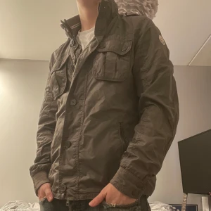 Moncler field jacket - Skitsnygg field jacket från moncler som är väldigt sällsynt med knappar och dragkedja. Skicket är bra med små tecken på användning. Den är i storlek 3 vilket motsvarar m och passar någon mellan 177-187. 