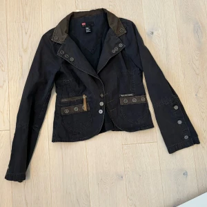 Svart kavaj från Diesel - Säljer en snygg svart kavaj från Diesel med unika detaljer. Kavajen har knappar och en cool design med kontrasterande sömmar. Perfekt för både vardag och fest! Storleken är M men mindre i form, passar mig perfekt som brukar ha XS/S. 