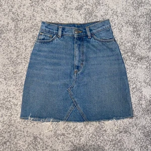 Jeanskjol från Monki - Säljer denna fina jeanskjol från Monki i storlek 32. Kjolen har en snygg passform och är fransig längst ner i kanten.💙🦋 Sömmen har gått upp lite längst ner vid dragkedjan, vilket man kan se på de sista bilderna. Men det är inget som märks💕