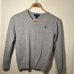 Snygg Ralph-Lauren V-neck övertröja - Stilig ljusgrå Polo-Ralph Lauren V-Neck.  Tunn och luftig.  Storlek: 14-16yrs(L). Passar som  XS/XXS  Pris går möjligtvis att diskuteras 