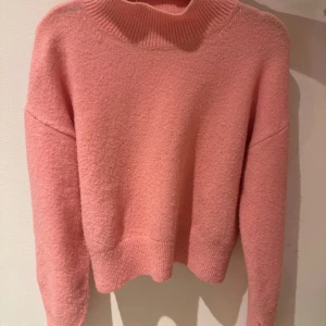 Rosa tröja från & Other Stories - Säljer en mysig rosa tröja från & Other Stories. Tröjan har en hög krage och långa ärmar, perfekt för kyligare dagar. Materialet är en blandning av polyester, akryl, ull och elastan vilket ger en mjuk och bekväm känsla. Passar utmärkt till både jeans och kjol.