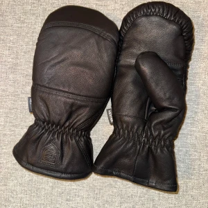 Svarta skinnvantar från Hestra - Säljer ett par svarta skinnvantar från Hestra. Vantarna har en stilren design med elastisk mudd för bättre passform. Perfekta för kalla dagar. Helt nya kunde ej lämna tillbaka pågrund att jag tagit av plomberingen. 