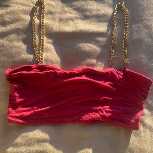 Röd tubtopp från Shein med kedjeband - Snygg röd tubtopp från Shein med guldfärgade kedjeband som axelband. Perfekt för en kväll ute eller en somrig dag. Toppen är i ett stretchigt material som ger en bekväm passform.