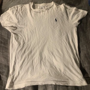 Vit t-shirt från Polo Ralph Lauren - Säljer en klassisk vit t-shirt från Polo Ralph Lauren med den ikoniska broderade loggan i blått på bröstet. T-shirten har en normal passform och är kortärmad, använd fåtal gånger. Tveka inte att höra av er vid intresse 