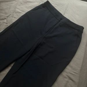 Svarta kostymbyxor från Academy - Snygga svarta kostymbyxor från Academy Elite. De har en klassisk design med dragkedja och knapp framtill. Perfekta för en stilren look.