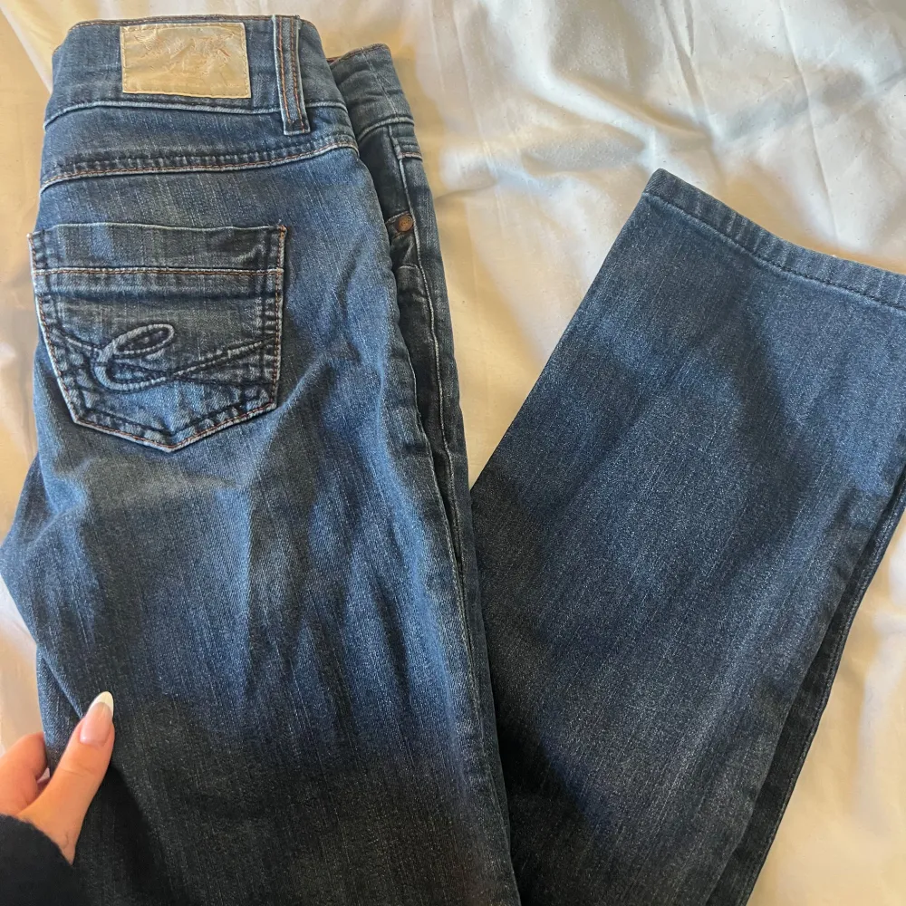 Snygga blå jeans från Esprit med dubbla knappar och klassisk femficksdesign. De har en diskret tvättad look och broderade bakfickor. Perfekta för en avslappnad stil.. Farkut & Housut.