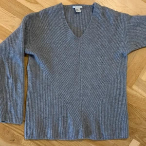 Grå kashmirtröja från H&M - Säljer en grå kashmirtröja från H&M. Tröjan har en v-ringad design och är ribbad med långa ärmar.