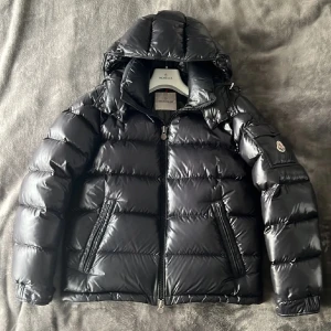 Svart Moncler Maya - Tja! Riktigt snygg Moncler jacka (Modell Maya) säljes! Stilren och passar till allting 🍾 Storlek 2 /sitter som S.  NFC tagg och liknande finns för äkthetsbevis, mycket bra skick, inga vattenfläckar eller missfärgningar.  Ett litet hål men syns ej vid användning, därav priset (bild i pm)‼️  Hör av er vid frågor å funderingar 🙌