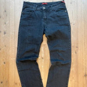 Mörkblå jeans från ML Jeans - Snygga mörkblå jeans från ML Jeans med broderade detaljer på bakfickorna. De har en klassisk femficksdesign och knappgylf. Perfekta för en avslappnad stil. De är vintage så har härligt slitage på sig. De är uppsydda några Cm, men om man skulle vilja ta väck sömmen görs de enkelt med sax. Står storlek 44 men sitter typ som ett par 32/32. Skriv vid frågor!