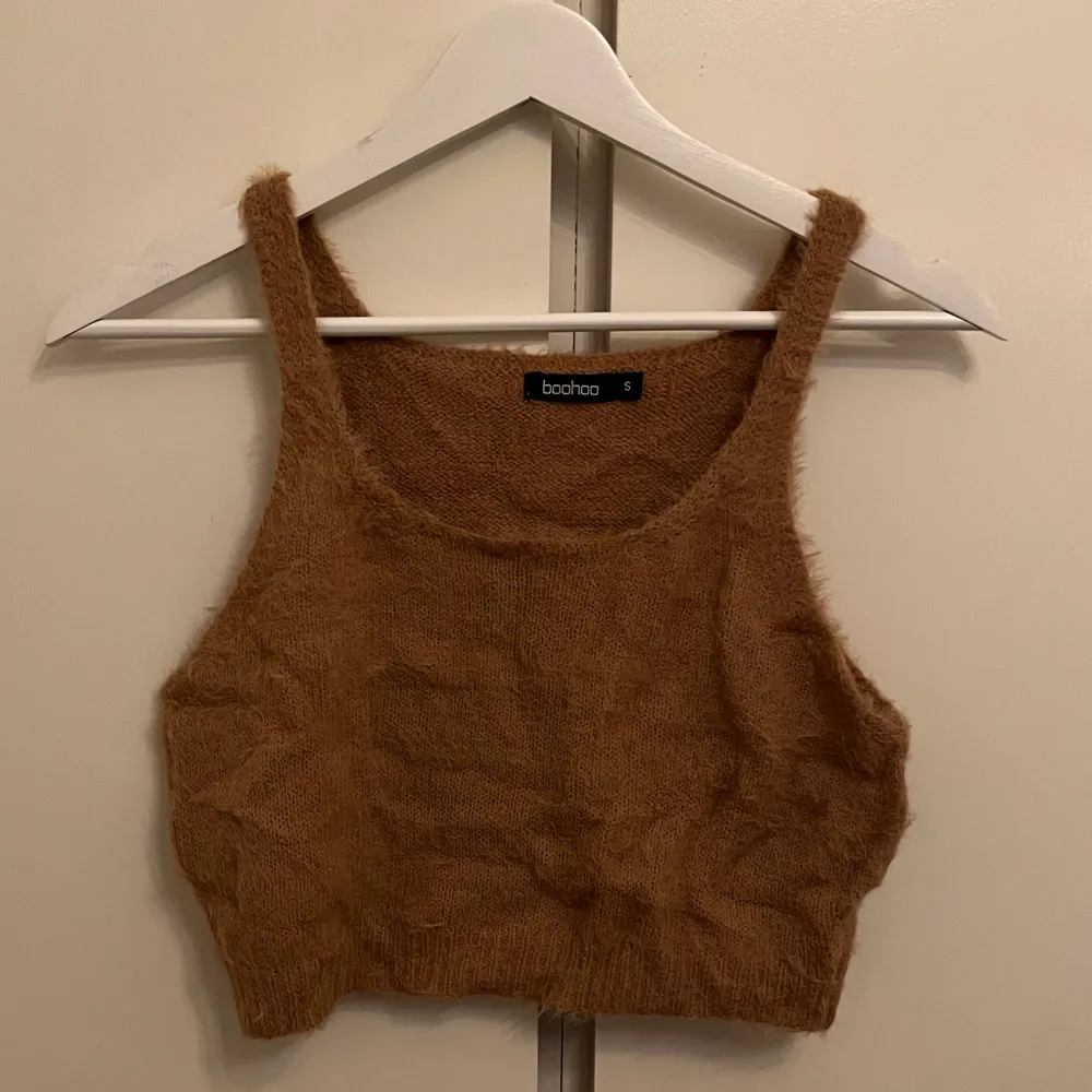 Säljer en brun fluffig topp. Den är ärmlös och har en croppad passform, perfekt för en trendig look. Materialet är mjukt och ger en mysig känsla.. Yläosat.