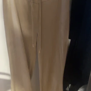 Beige mjukisbyxor från Gina Tricot - Säljer ett par bekväma beige velour mjukisbyxor från Gina Tricot. Byxorna har en avslappnad passform med dragsko i midjan för justerbar komfort. Perfekta för en avslappnad stil.