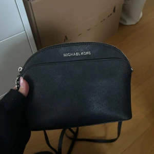 Svart axelväska från Michael Kors - Svart axelväska från Michael Kors. Väskan har en praktisk dragkedja upptill och en justerbar axelrem. Den är i fint skick!