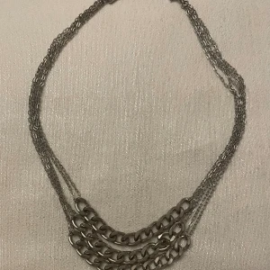 Silverfärgat halsband med flera kedjor - Elegant halsband i silverfärg med flera tunna kedjor och större länkar i mitten. Perfekt för att ge en stilren touch till din outfit.