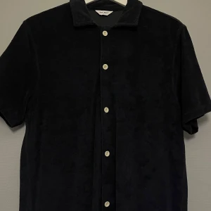 Svart kortärmad skjorta från East West - Snygg mörkblå skjorta från East West i frotté med korta ärmar och knappar framtill. Perfekt för en avslappnad stil.