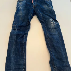 Blå jeans från DSQUARED2 - Snygga blå jeans från DSQUARED2 med slitna detaljer och en cool, vintage look. De har en klassisk femficksdesign och knappgylf. Perfekta för en avslappnad stil med en touch av edge.